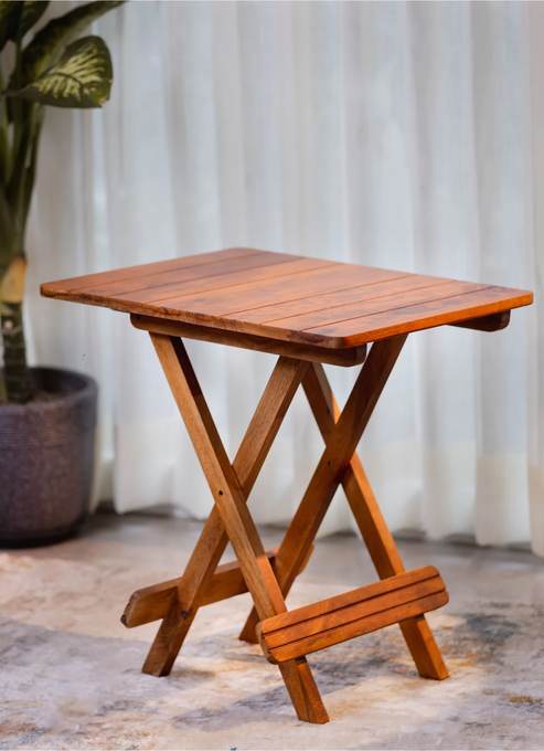 Folding side table in a honey finish beside a plant
