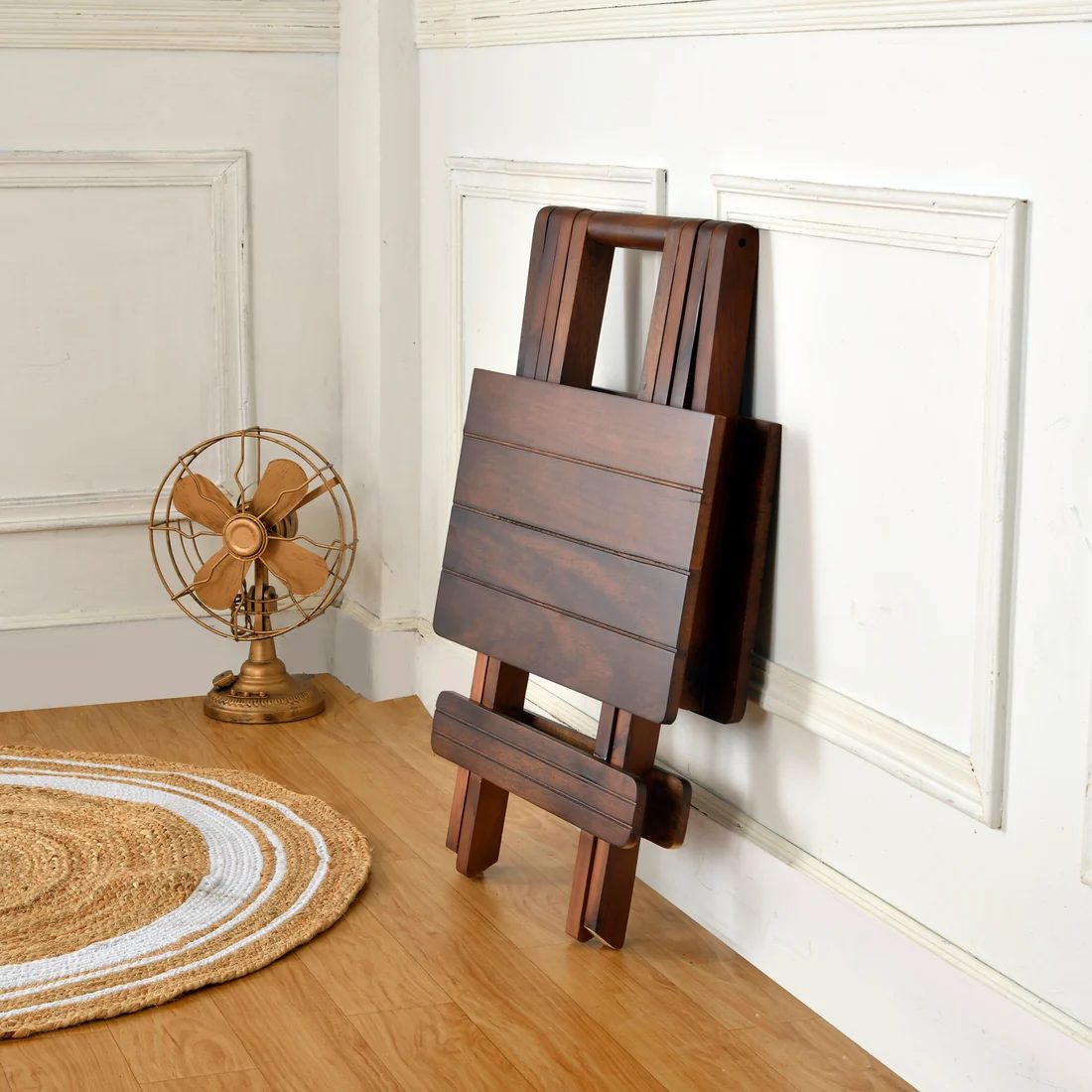Walnut folding table folded flat and stood against a wall